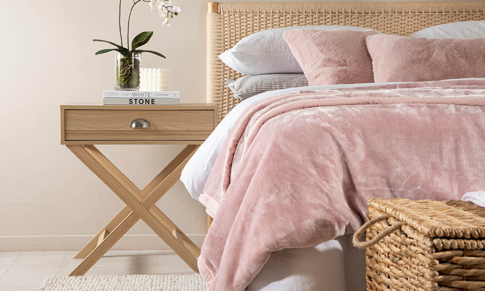 Bedside Table next to pink quilt covered bed