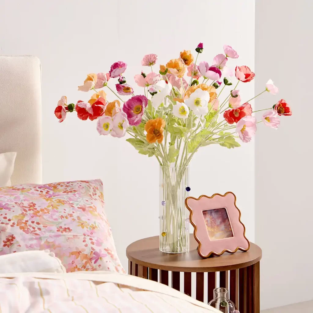 Bouquet of artificial flowers in vase on bedside table