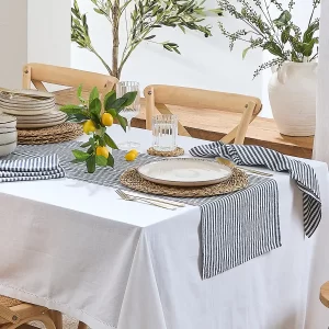 Outdoor dining set up with a blue stripe table runner and white tablecloth.