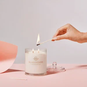 Glasshouse candle on light pink table being lit.
