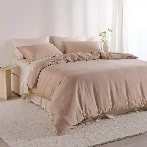 A bed styled with a light beige bamboo cotton sheet set and a taupe bamboo cotton quilt cover set.