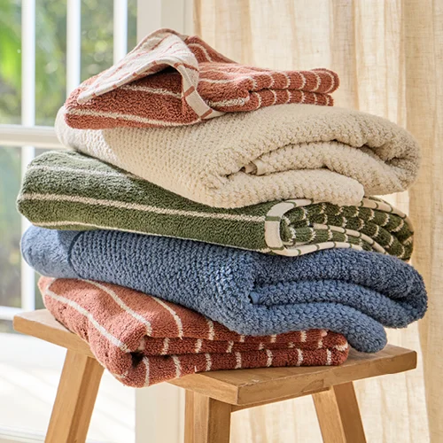 Stack of bath towels with chocolate stripe, green stripe, blue and cream.