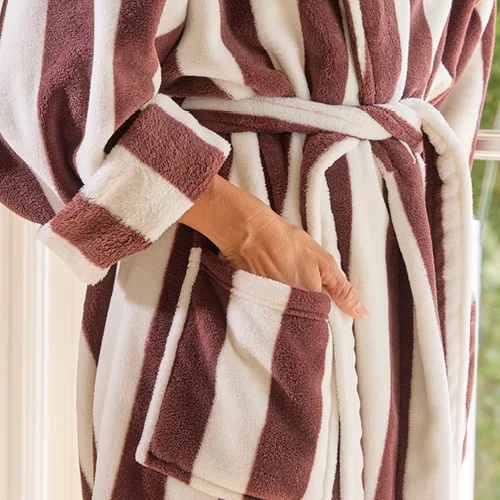 Woman wearing chocolate and white striped robe with hand in pocket