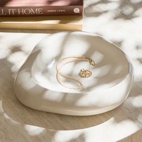 Rustic white display tray with gold necklace inside.