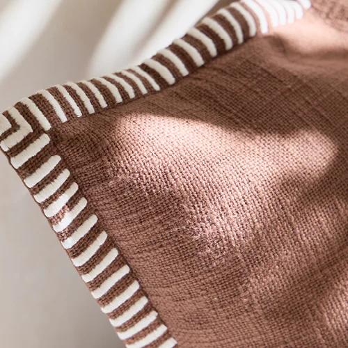 Chocolate cushion with white and chocolate striped edges.