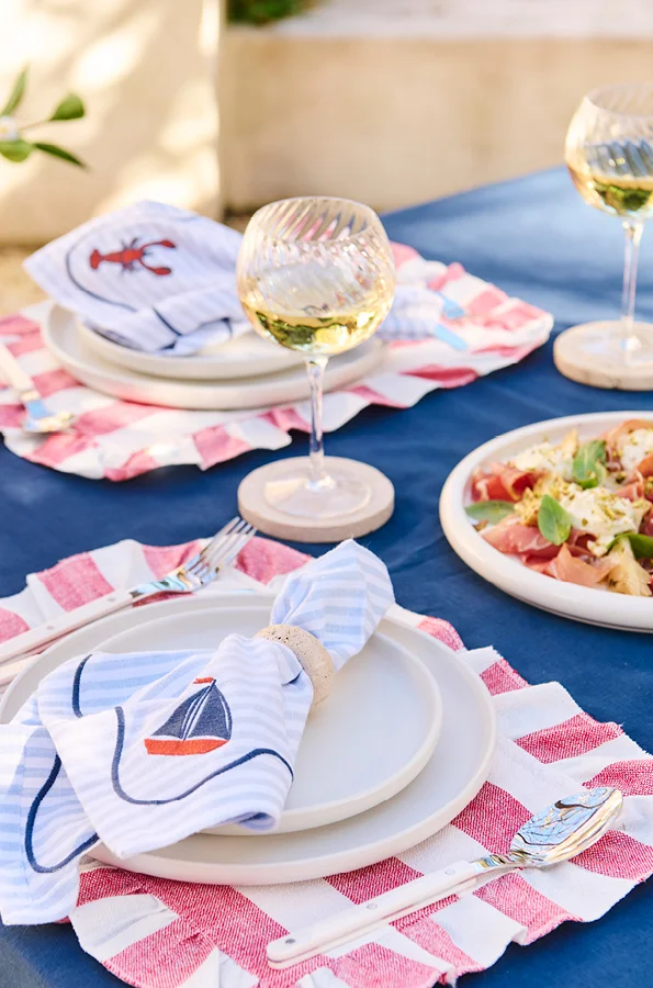 Nautical themed diner table with blue striped napkins on white dinnerware